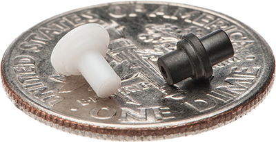Two very small plastic parts sitting atop a dime